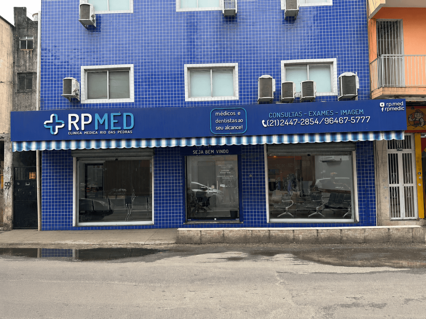 Fachada azul da RP Med, com o letreiro da clínica e o toldo listrado na entrada