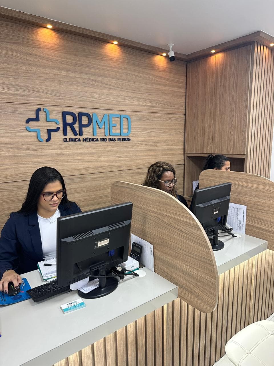 Equipe da recepção da RP Med atendendo pacientes nos guichês de atendimento